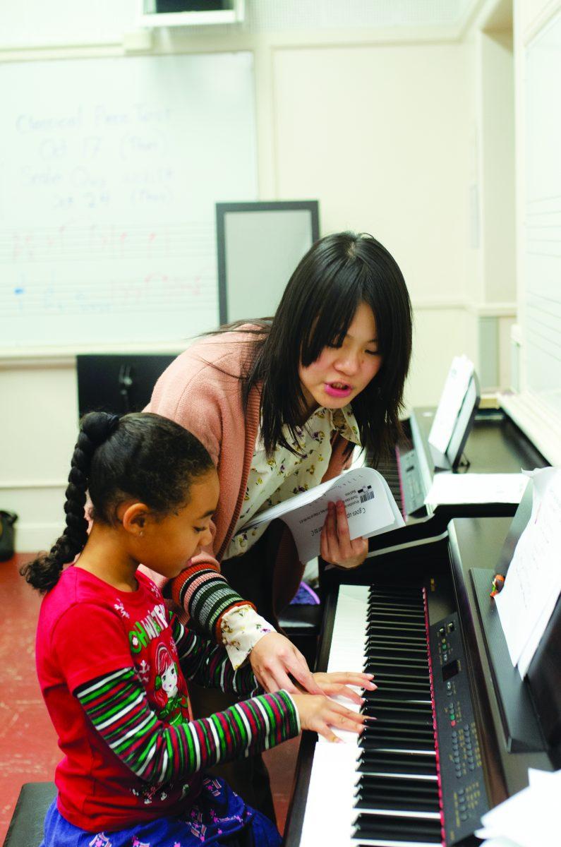 Music graduate student Tracy Chen helps Amber as she learns how to play the piano. Chen is the instructor of the music program.