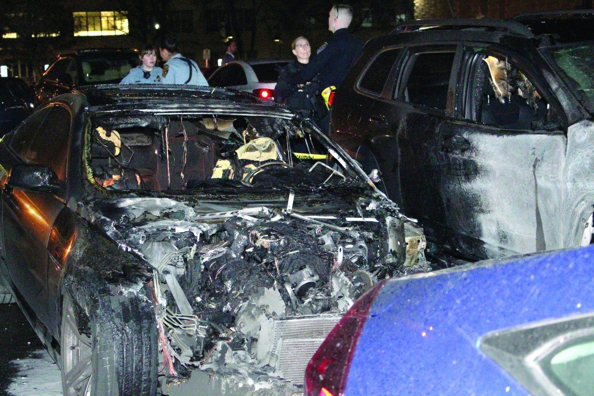 University Police Department officers gather around a burnt and damaged BMW (left) that caught on fire in Lot 4 near Boccardo Business Center Wednesday night. Vicente Vera | spartan daily