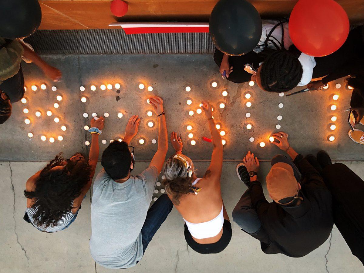 Members of Black Liberation And Collective Knowledge (BLACK) Outreach San Jose, a Black activist community collective, and other San Jose residents light candles in front of City Hall Saturday. Blue Nguyen/Spartan Daily