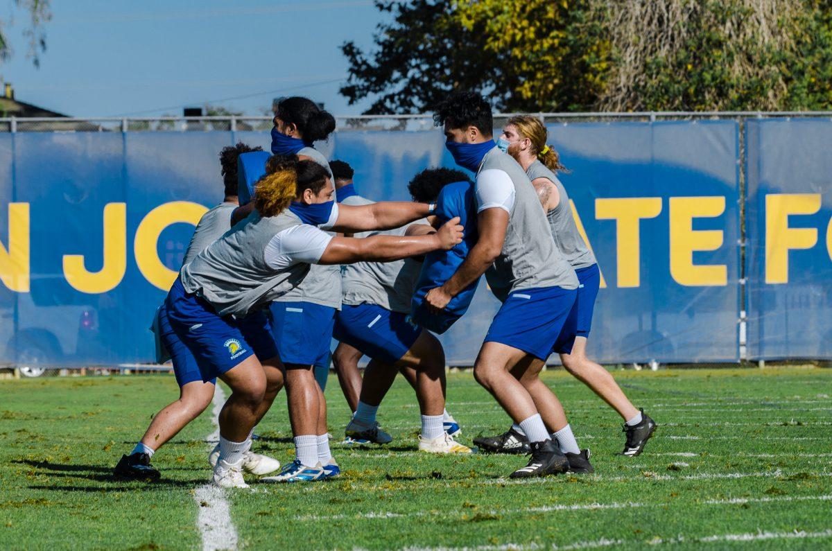 San Jose State football players run defensive drills while wearing face masks on Tuesday on the practice field at South Campus. Blue Nguyen | Spartan Daily