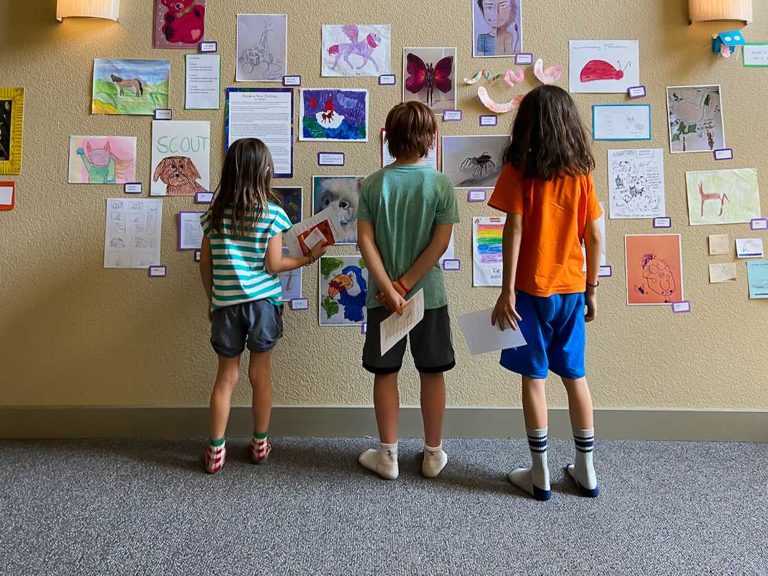 Three young artists view their contributions to the &#8220;Animals in Art and Poetry&#8221; exhibit at the Ryland Mews apartment complex in July. Photo courtesy of Amy Brown.