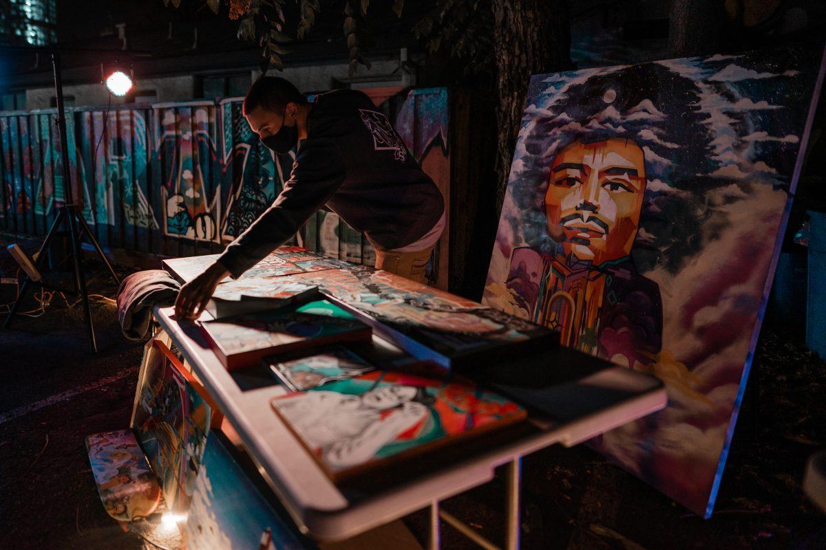 Docter Ques sets up his art for sale at the San Jose Peace and Justice Center during an open mic night hosted by Stories for Solidarity on Nov. 7. Photo by Blue Nguyen.