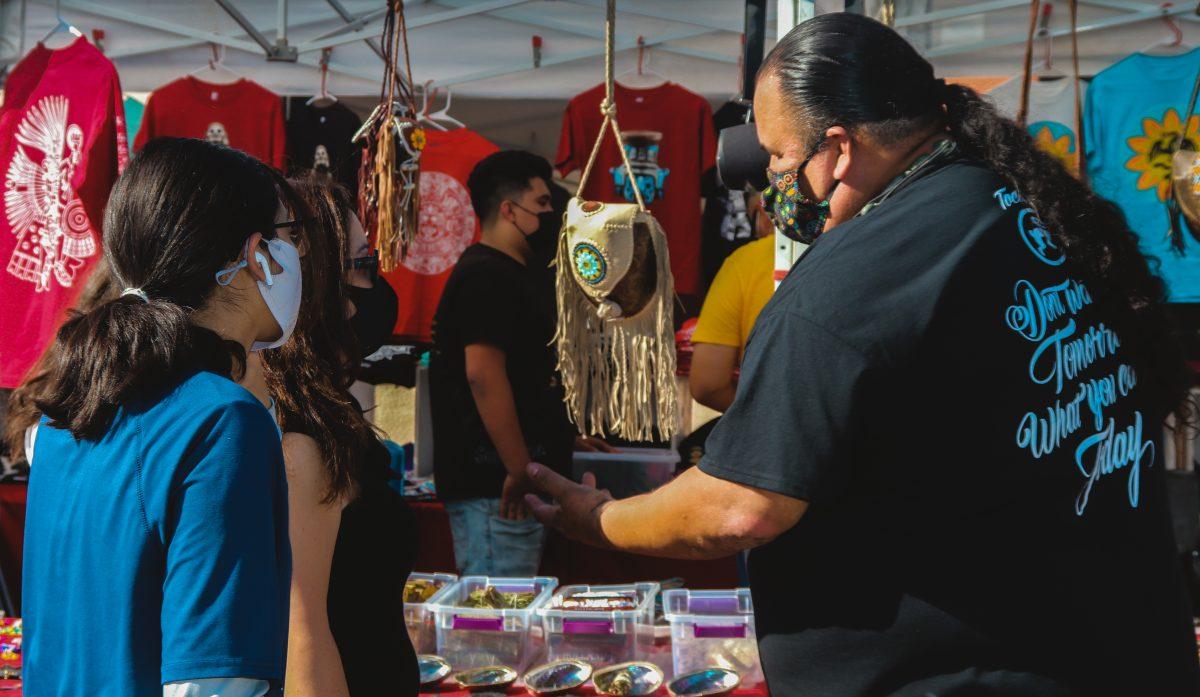 Yei Tochtli Mitlalpilli, co-founder of Tochtli Wear, talks to a customer at his tent during the D&#237;a de los Muertos market on Oct. 31. Photo by Isalia Gallo