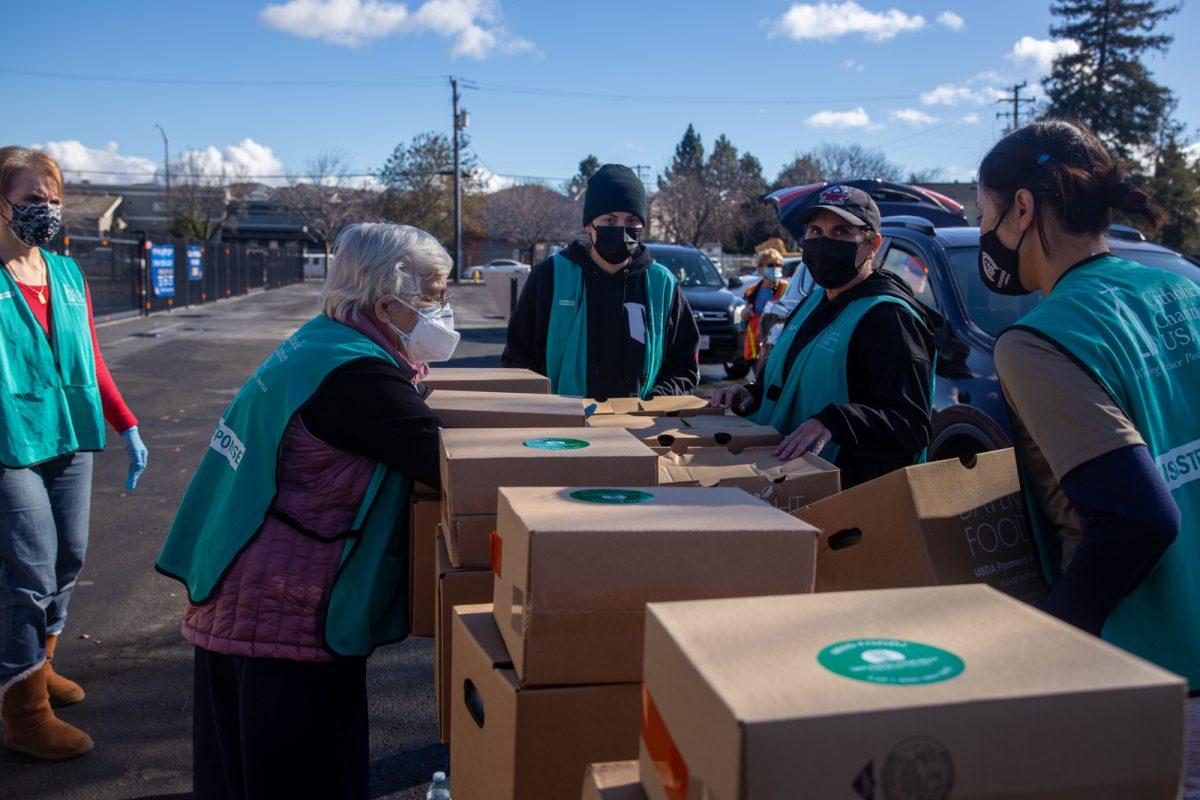 Volunteers from the Catholic Charities of Santa Clara County gather in the parking lot of St. Lucy Catholic Parish Friday to organize boxes of food for the community. Yami Sun | Spartan Daily