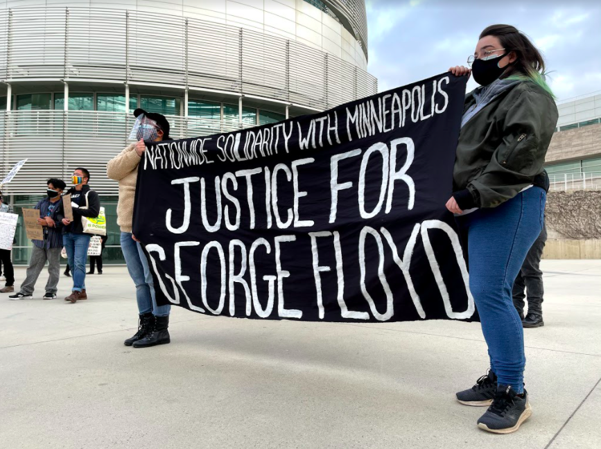 San Jose residents Sabrina (right) and Maricon (left), who prefer to be identified by their first names, hold a banner at city hall Monday I Photo by Blue Nguyen