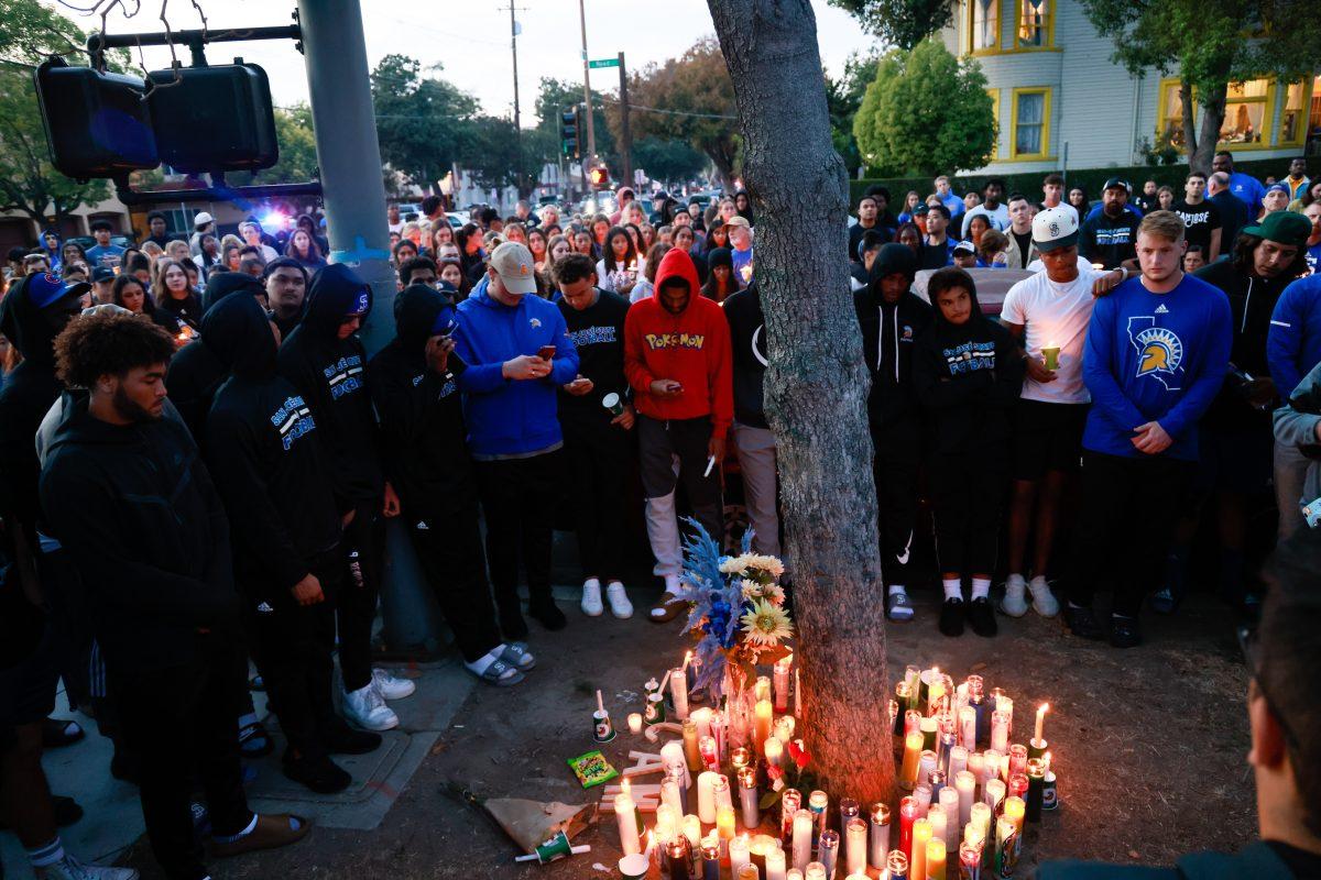 Hundreds of San Jose community members gather in mourning on Tenth and Reed streets Friday evening to memorialize Camdan McWright, an 18-year-old SJSU freshman football player who died that morning at the intersection. Nick Zamora | Spartan Daily