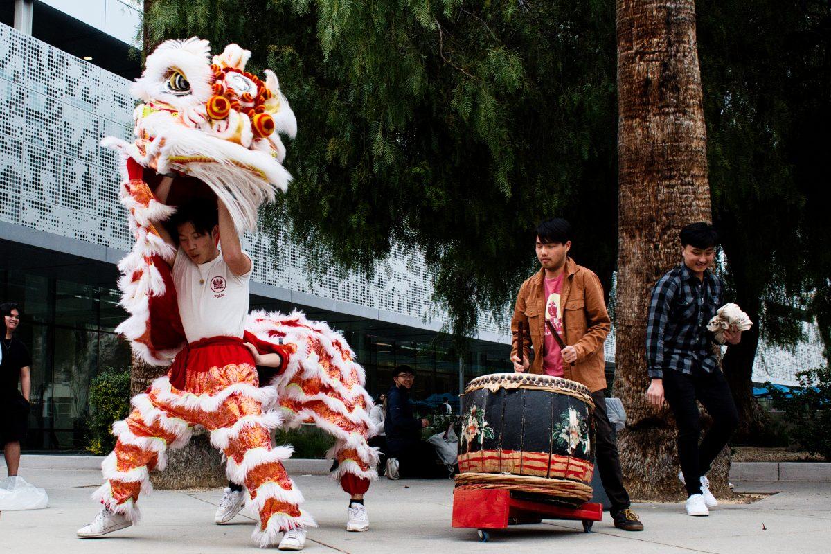 Lion dancers Phillip Tran and Alvin Fung perform next to Justin Vo, third year biology and physiology student playing the drums.