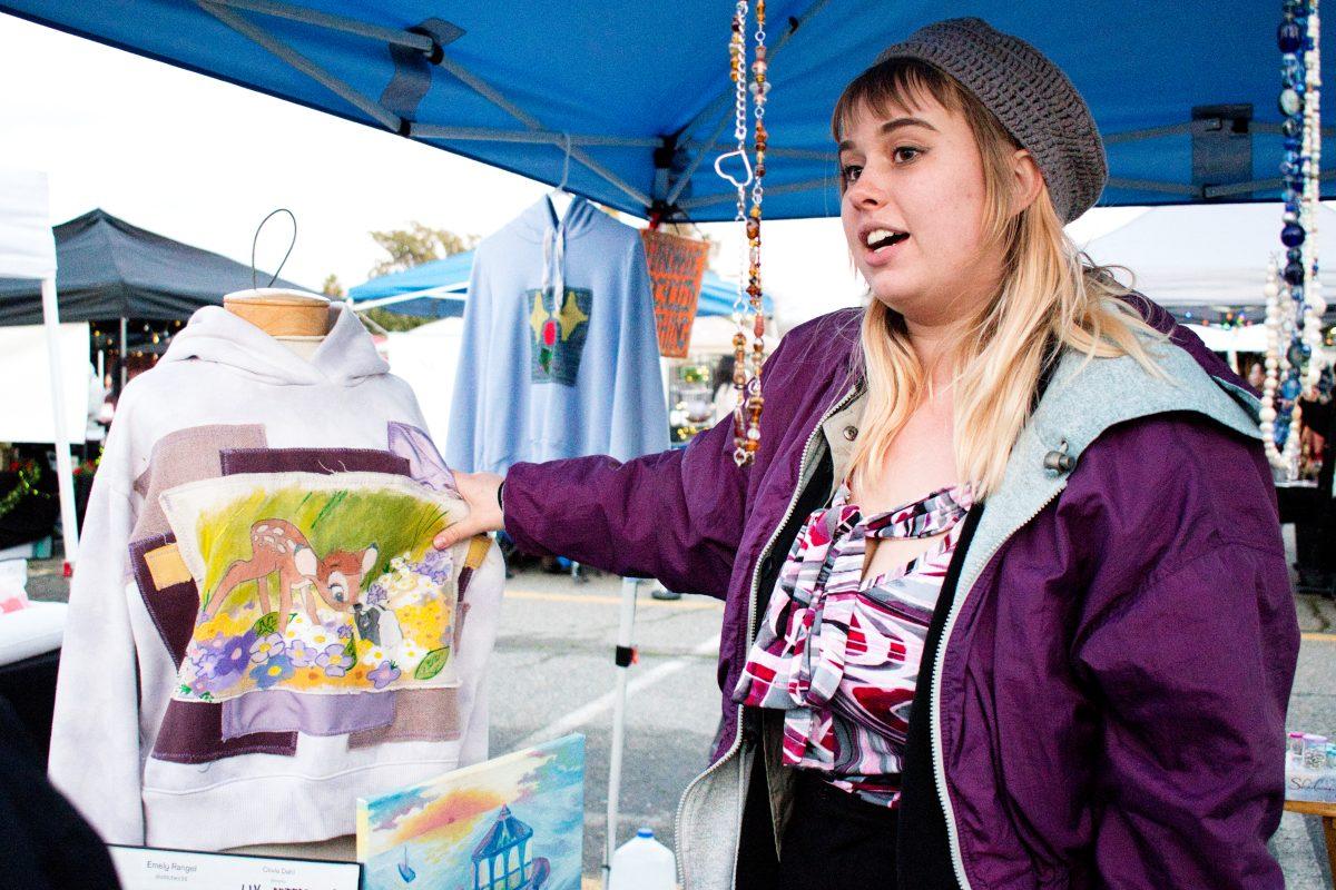 Emily Rangeo, one of the four founders of stitches be trippin, shows visitors at Sweet and Street a painted and embroidered hoodie by her sister.
