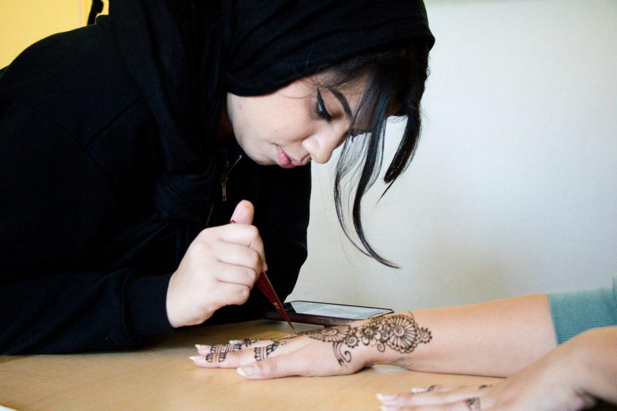 Maryam Moshref does henna on forensic biology senior Desiree Castro&#8217;s right arm in her dorm at Campus Village A on Thursday, Feb. 23.