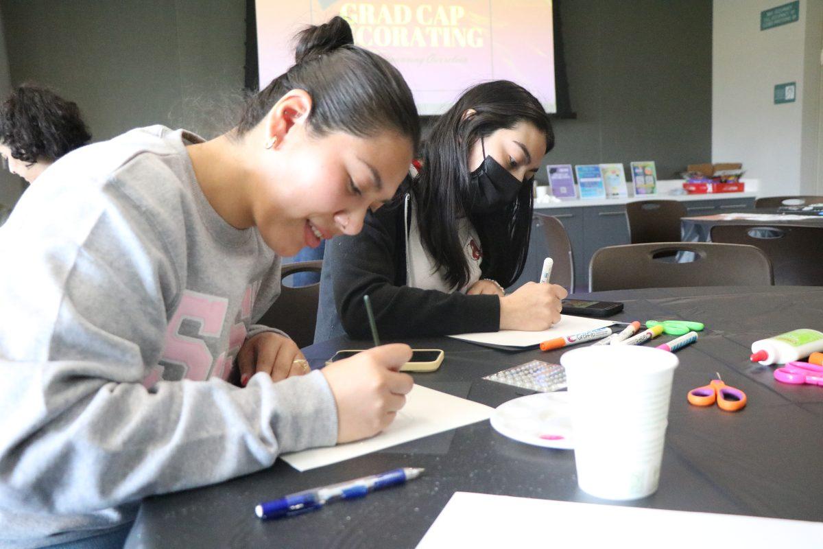 Sociology seniors Vanessa Sepulveda (left) and Victoria Mendez (right) decorate their graduation caps in the Student Union on Tuesday afternoon.