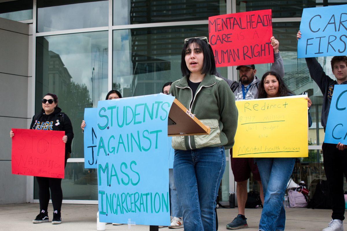 Dora Gurrola, a Students against Mass Incarceration team member and rally speaker, presents SAMI's demand for fund reallocation from Santa Clara Country's Board in front of City Hall on Thursday.