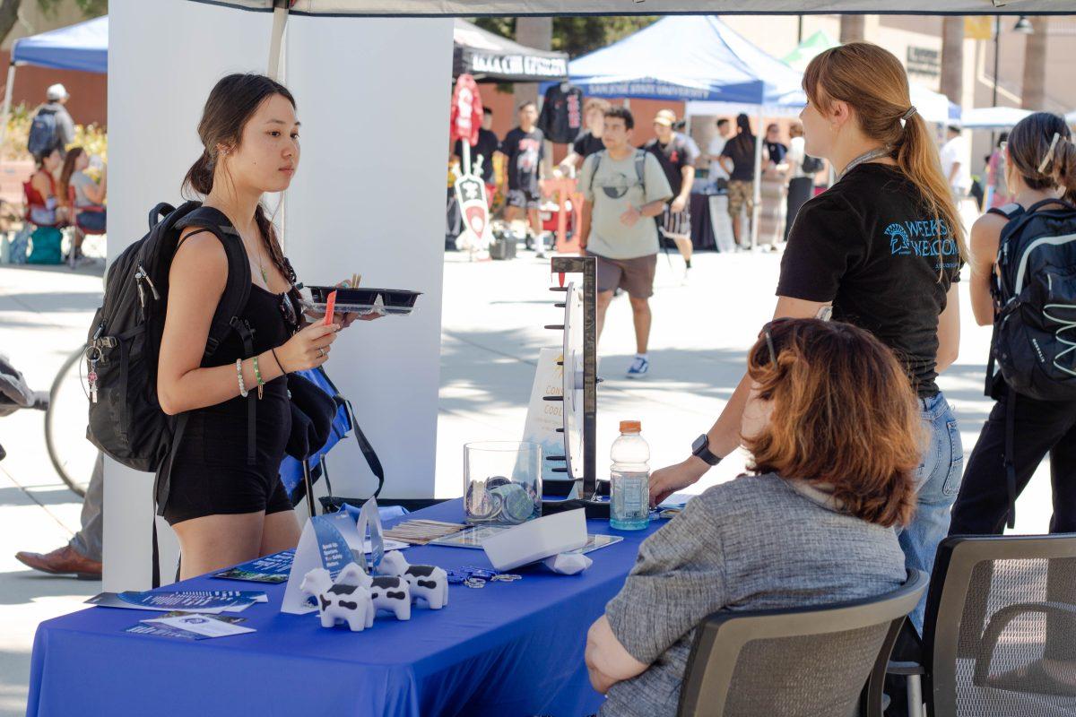 Jessica Short (right) talks to students passing by Seventh Street Plaza at the consent cooler tabling events during Weeks of Welcome on Wednesday morning.