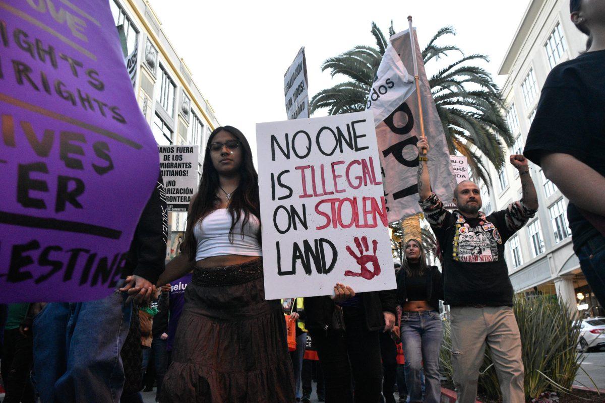 Protesters at a post-inauguration protest on Jan. 20 walk through Santana Row with signs showing their support against Trump&#8217;s policies targeting immigrants.