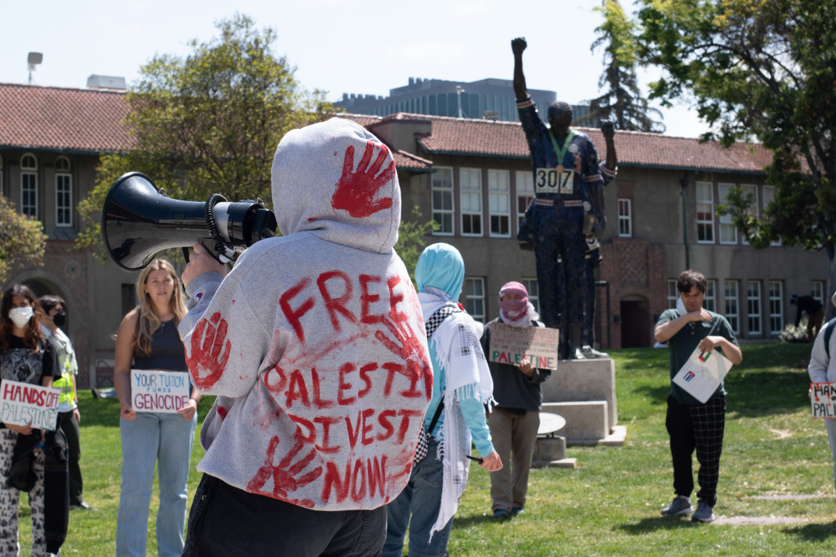 A student protester from SJSU Students for Justice in Palestine speaks to protesters with a megaphone outside Dwight Bentel Hall near the Olympic Black Power Statue.