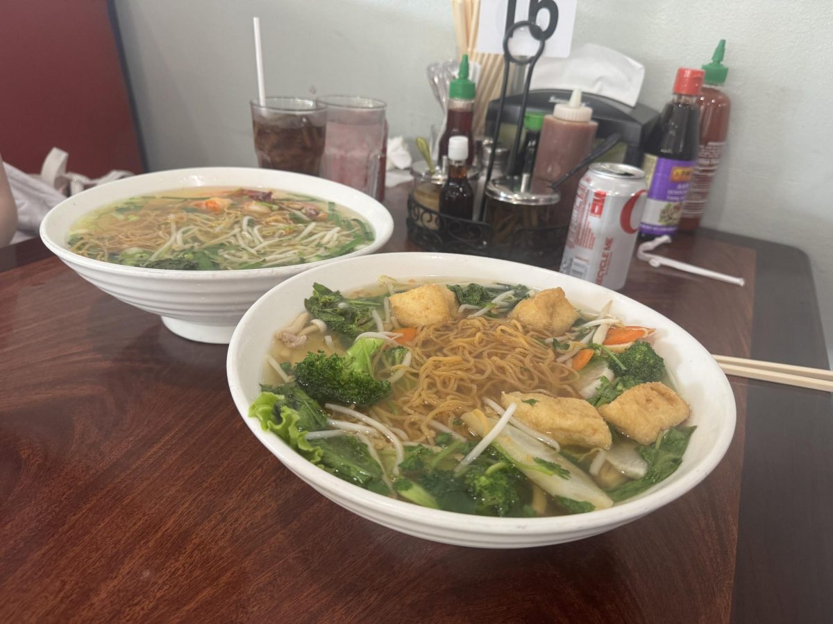 A steaming warm bowl of Vietnamese vegetable yellow noodle soup, mì chay khô, sits alongside another noodle soup at Kali Noodles and Tea Bar.