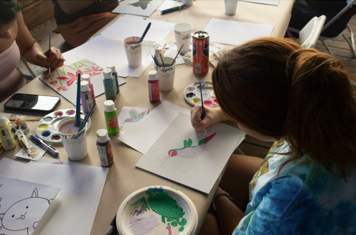 Hailey Wiley, a third-year nutrition and dietetics student, paints a hummingbird on cardstock while recalling a childhood memory.