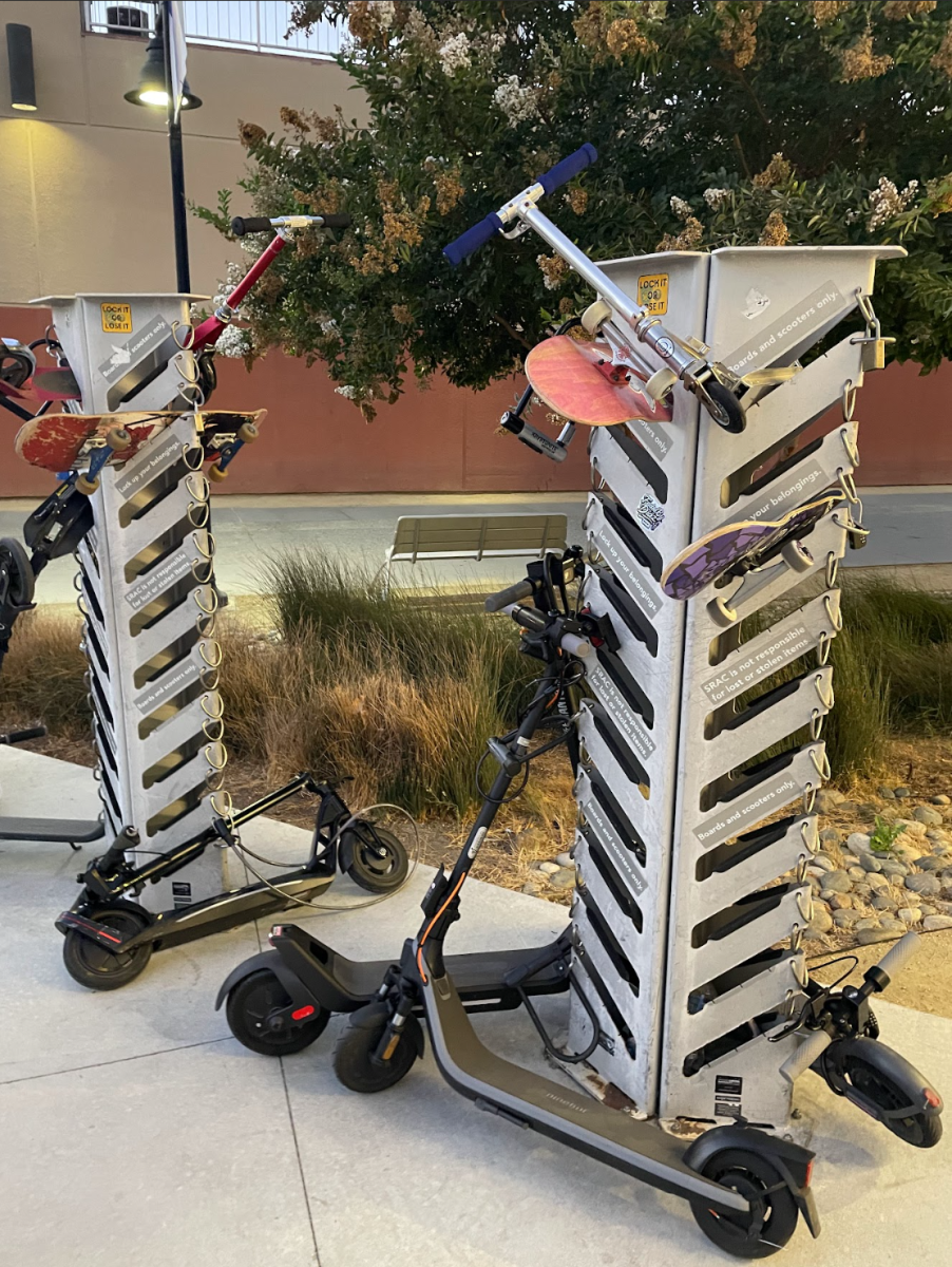 A rack of skateboard and scooters locked up near 7th Street on Campus.