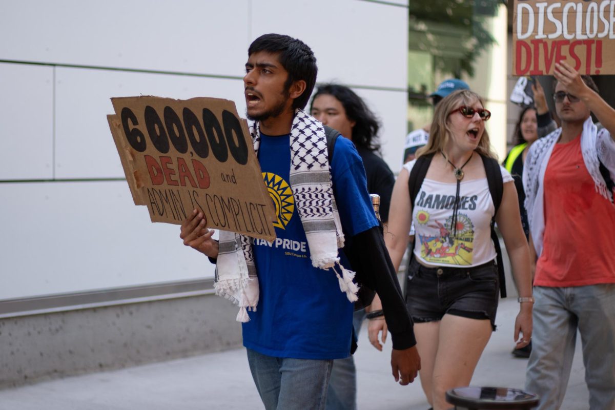 Students hold signs protesting SJSU’s partnership with Lockheed Martin outside the Student Union on Wednesday.