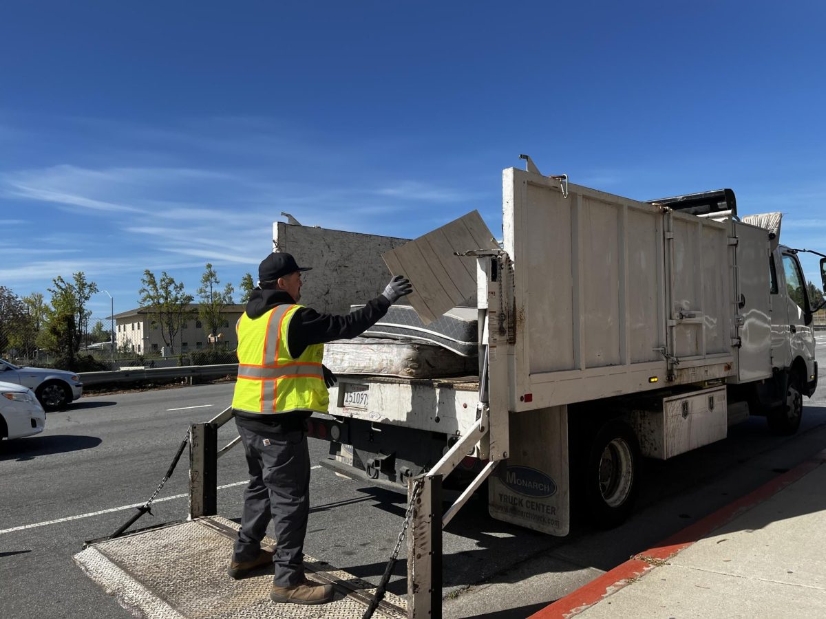 A City of San José worker piles wood, mattresses and various items in the back of a truck after clearing an area that experienced illegal dumping.
