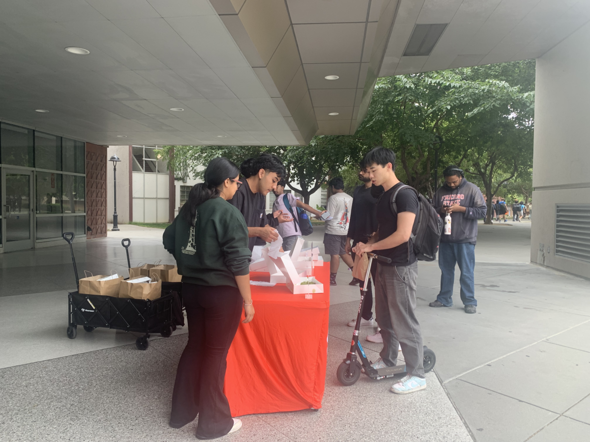 DoorDash Campus Launcher program ambassadors sit outside of the Martin Luther King, Jr. Library to hand out mochi donuts to students.