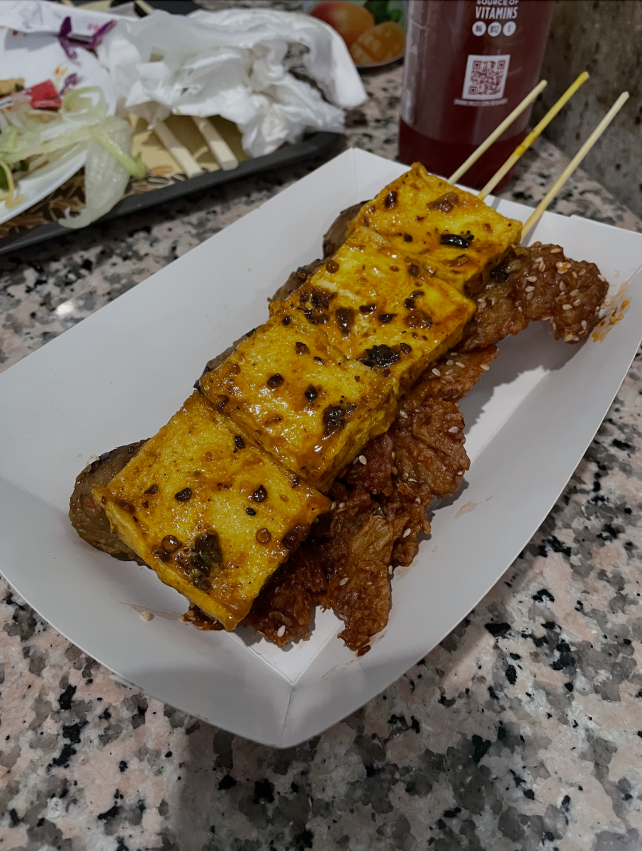 Three different types of vegan kabobs  marinated with various seasoning and spices from the restaurant Tofoo Com Chay lay stacked in a paper boat.