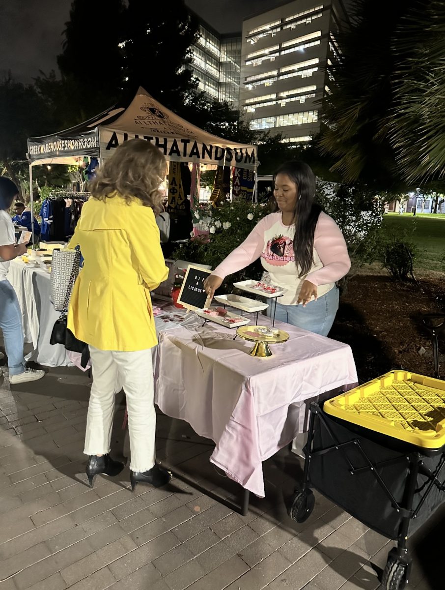 Alaiyah Holland, owner of Dip-A-Licious (right) gives out treats to San José State President Cynthia Teniente-Matson during an event.