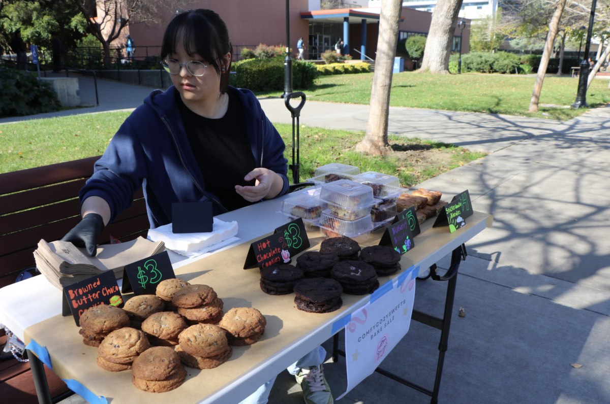 Katelan Liang sets up her bake sale table in front of the Science Building with a display of baked goods on Monday. 