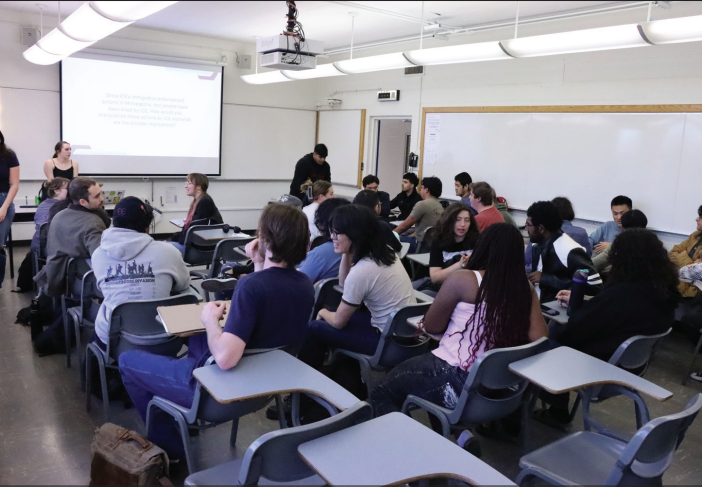 Students sit in Dudley Moorhead Hall in Room 356 talking about immigration agents.