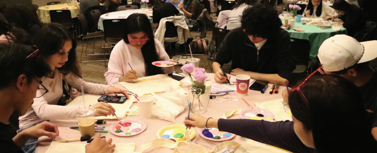 Students sit alongside each other painting tote bags and canvases while drinking free Nirvana Soul tea. 