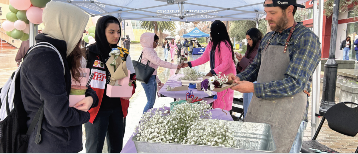SJSU students wait in the rain to get their choice of assorted flowers wrapped by a Pixie Pop Ups Vendor at the Petals and Pour event on the Seventh Street Plaza.