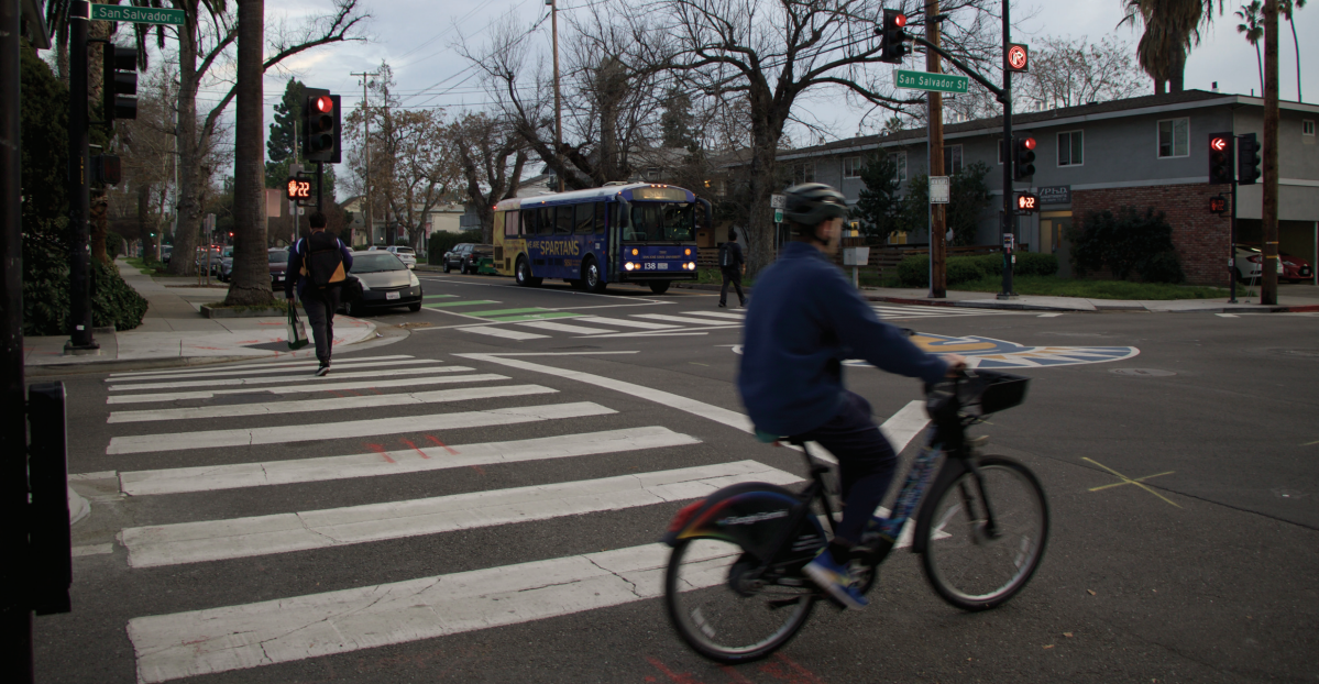 Pedestrians and a bicyclist safely cross at the designated walk time at the East San Salvador and South Seventh Street intersection.