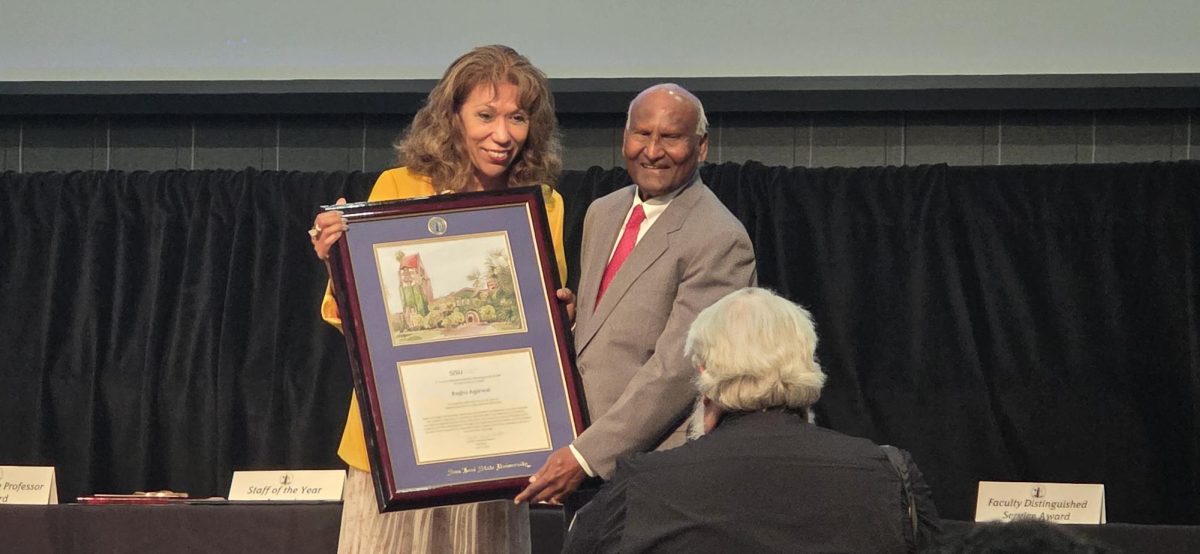 SJSU President Cynthia Teniente-Matson smiles for the camera while presenting an award commemorating Raghu Agarwal, professor and graduate program coordinator of mechincal engineering, for 45 years of service to SJSU.