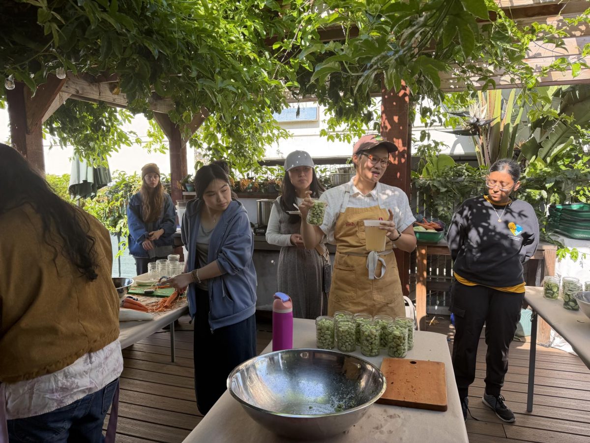 Chef Linh Vong explains how to store the pickled fava beans in a mason jar to a group of students at the Campus Community Garden on Thursday.