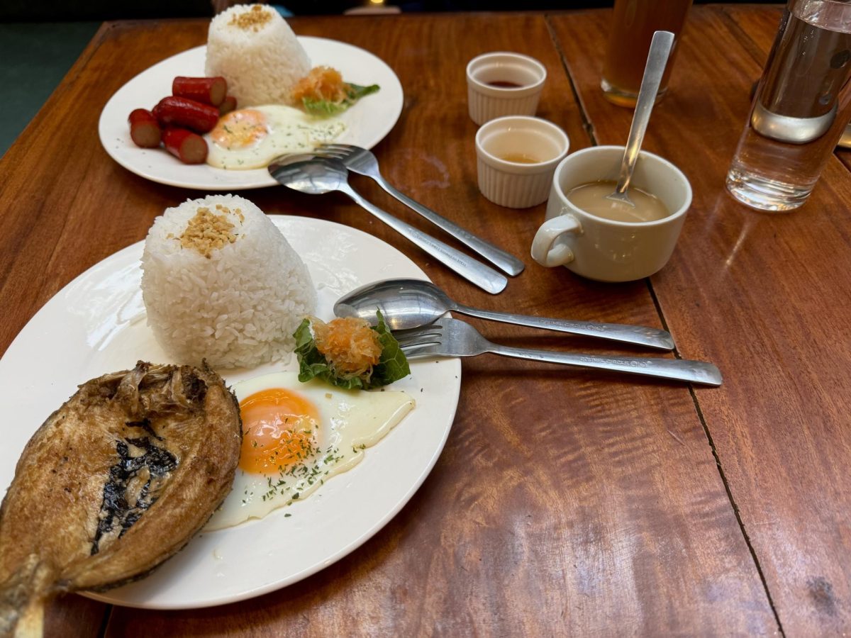A plate of bangus, hotdogs, garlic fried rice and sunny side up egg sits plated at a restaurant in the Philippines.