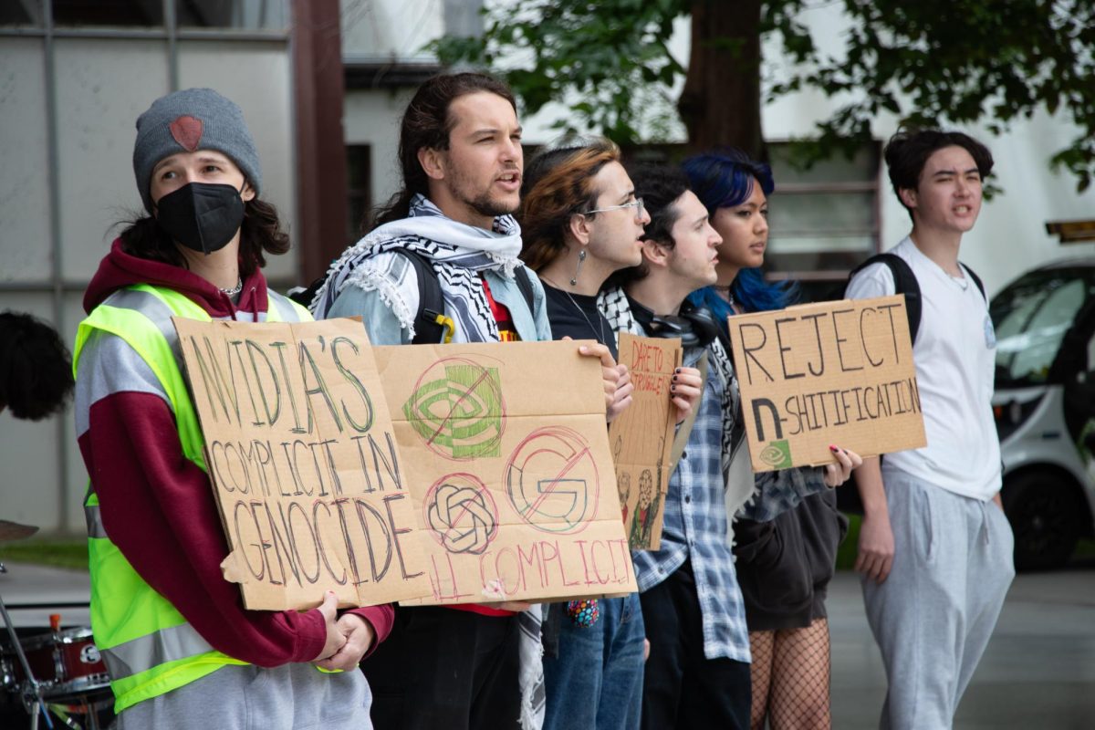 Students hold signs protesting AI companies' presence on campus in front of the Martin Luther King, Jr. Library on Wednesday.