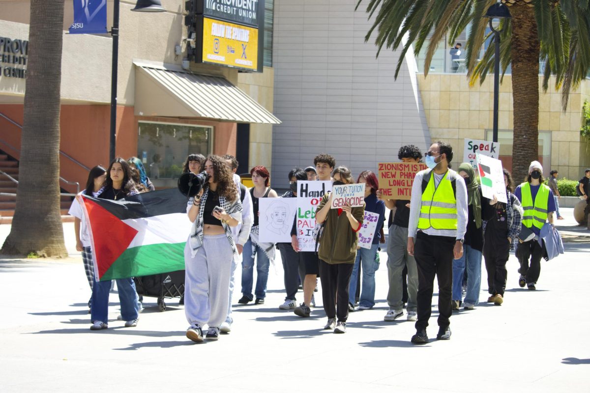 Maya Abou Kewik, a third-year psychology student and president of Students for Justice in Palestine, leads anti-war protest down Seventh Street. A student can be seen holding the Palestinian flag with others holding signs.