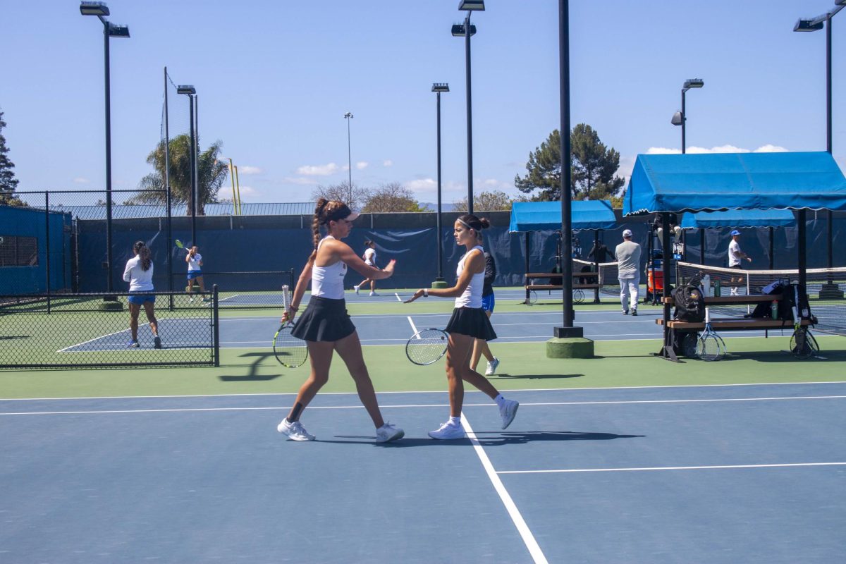 Emma Fantousis and Soledad Fayos Capilla, SJSU sophomores, reach for a high five after scoring a point while playing doubles. Capilla and Fantousis were defeated 6-1.