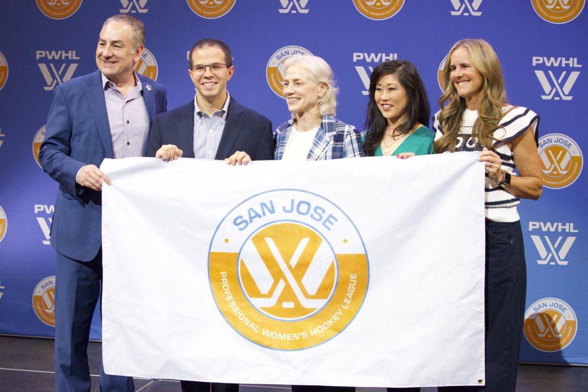 From left: Jonathan Becher, Royce Cohen, Amy Scheer, Kristi Yamaguchi and Brandi Chastain pose for a picture onstage, holding the flag representing the PWHL San José expansion team.